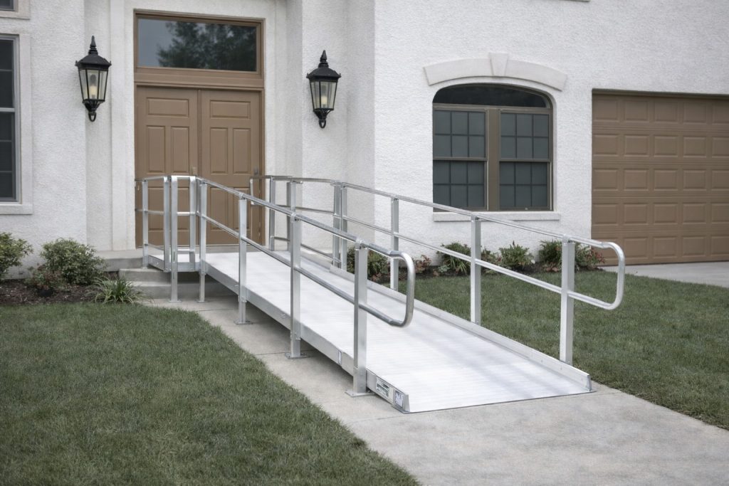 ADA-compliant aluminum wheelchair ramp installation at white stucco home with dual handrails and entry landing in Covington Louisiana