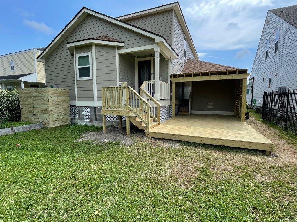 New pressure-treated wood deck with stair access and covered patio structure installed at a residential home in Covington, LA.