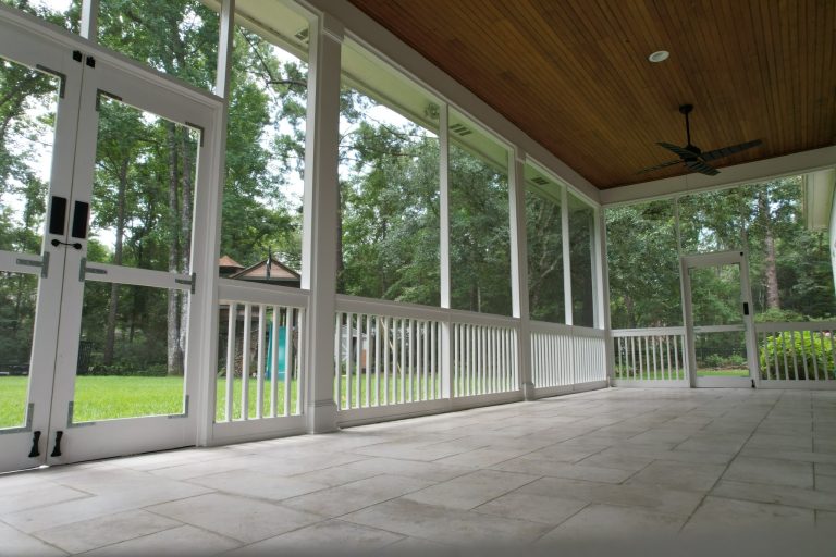 Custom screened-in porch installation in Covington, Louisiana featuring white framing, wood tongue-and-groove ceiling, tile flooring, and ceiling fan.