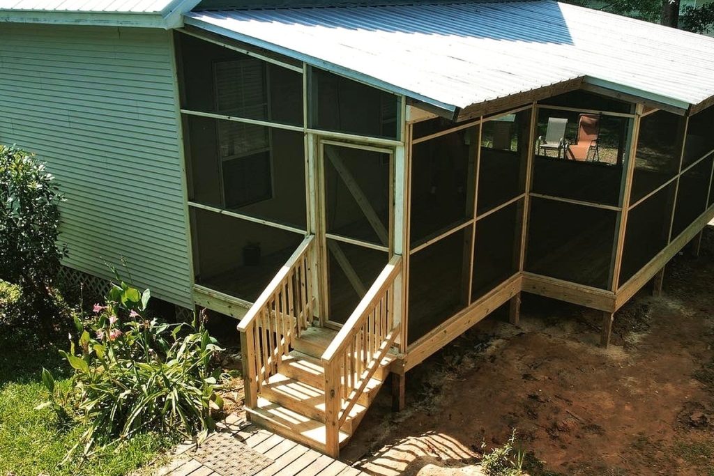 Custom screened porch addition with pressure-treated wood framing, screened walls, and entry stairs installed on a South Louisiana home
