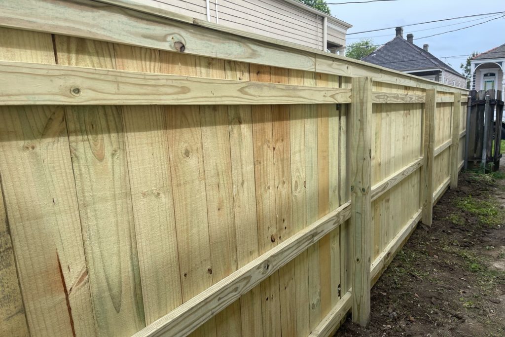 Pressure treated pine privacy fence installation in Covington Louisiana with 3-rail support and capped top