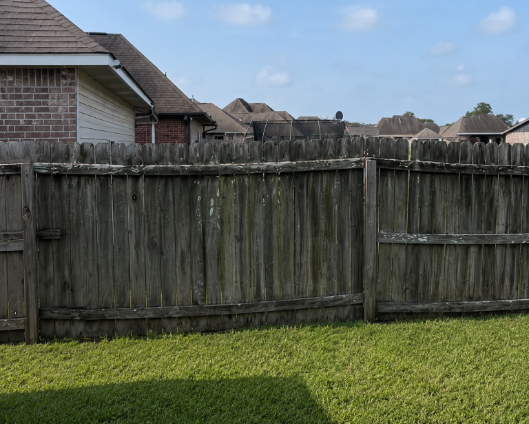 Old weathered wood privacy fence with leaning sections and aging fence boards in a suburban backyard needing fence repair in Covington Louisiana.