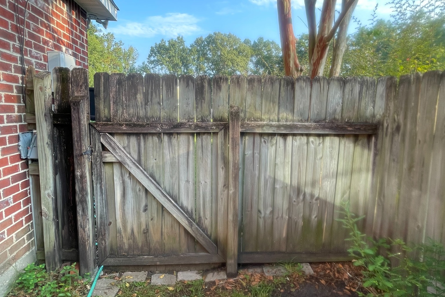 Weathered privacy fence with missing pickets and wood rot before professional fence replacement in South Louisiana.