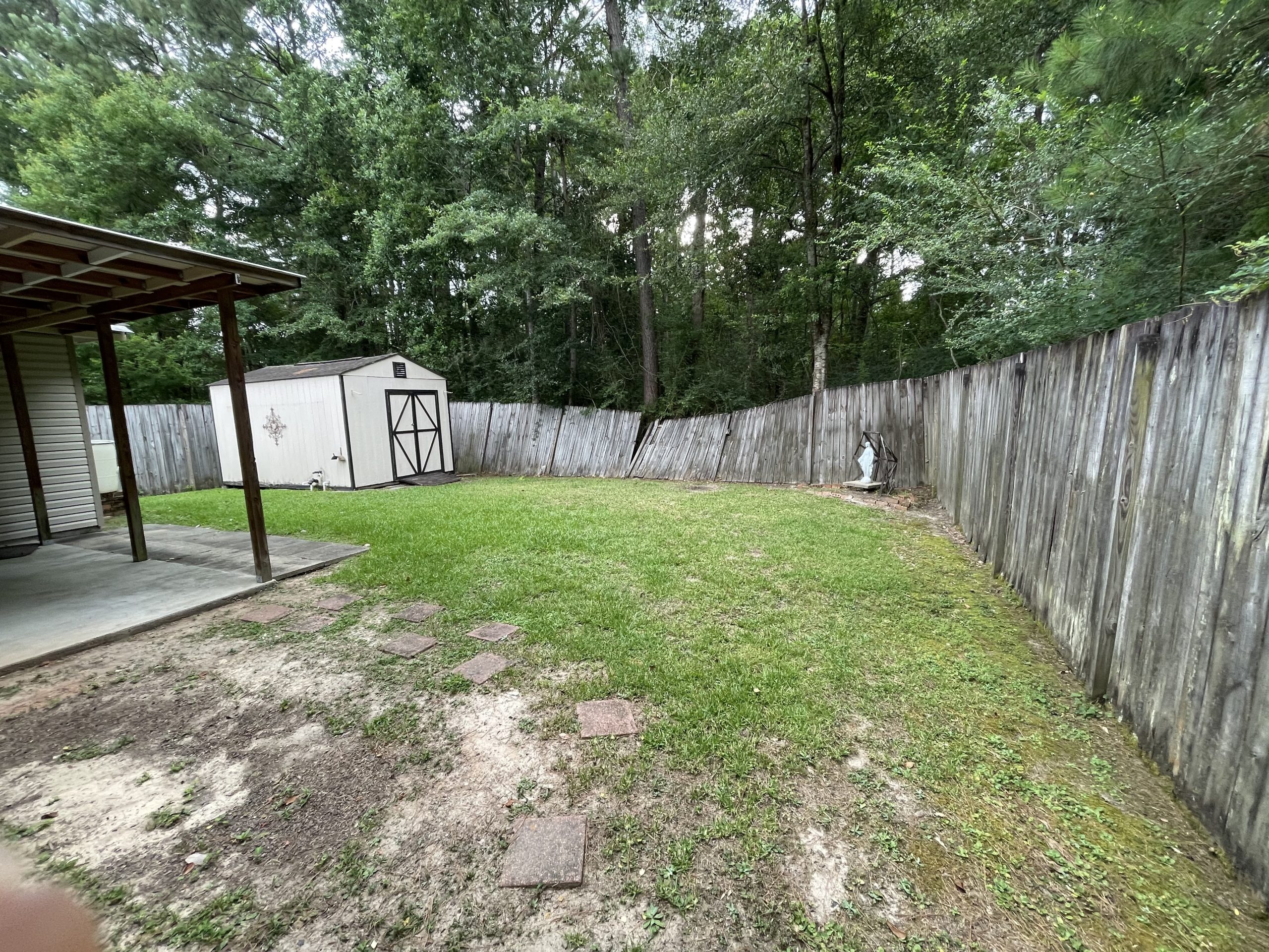 Leaning and weathered wood privacy fence in backyard in Covington, Louisiana