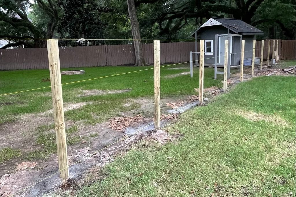 Pressure-treated pine fence posts set in concrete and aligned for a privacy fence installation in Covington, LA